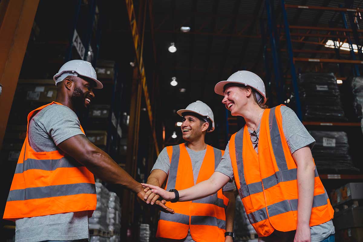 A Group of Diversity warehouse workers giving hand for high-five after success the project and celebrating together in a distribution center warehouse.